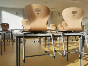 Bright and tidy empty classroom with wooden chairs and tables ready for students.