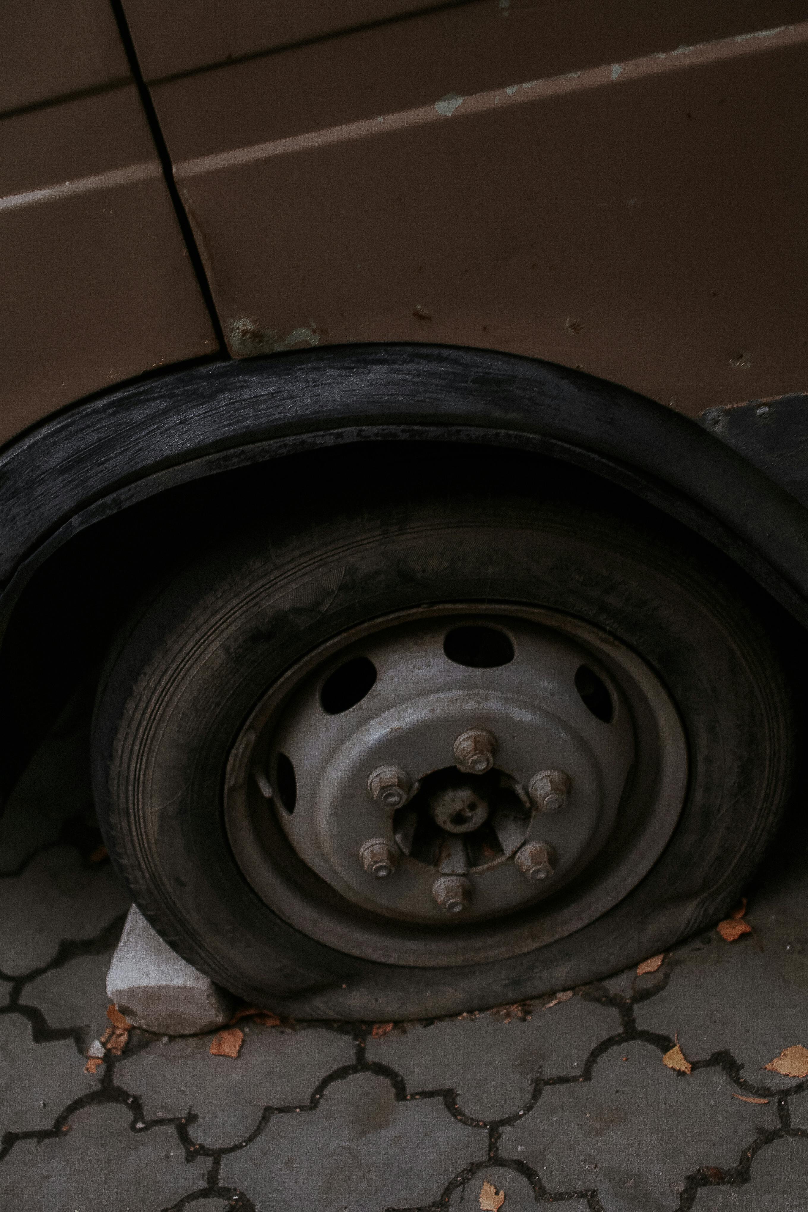 Detailed view of a flat tire on a car parked on a paved surface outdoors.